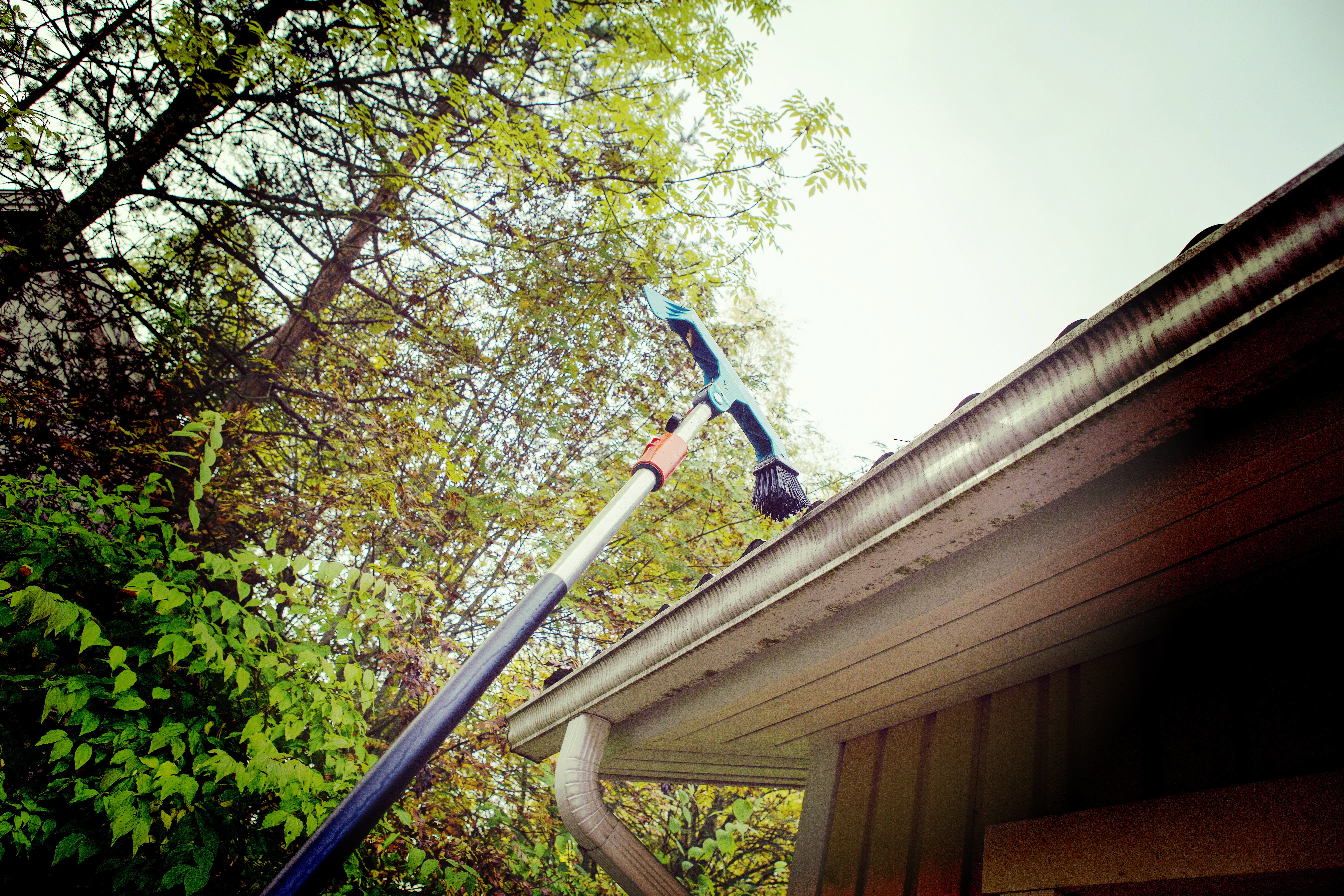 extended tool going up on a roof for cleaning gutters