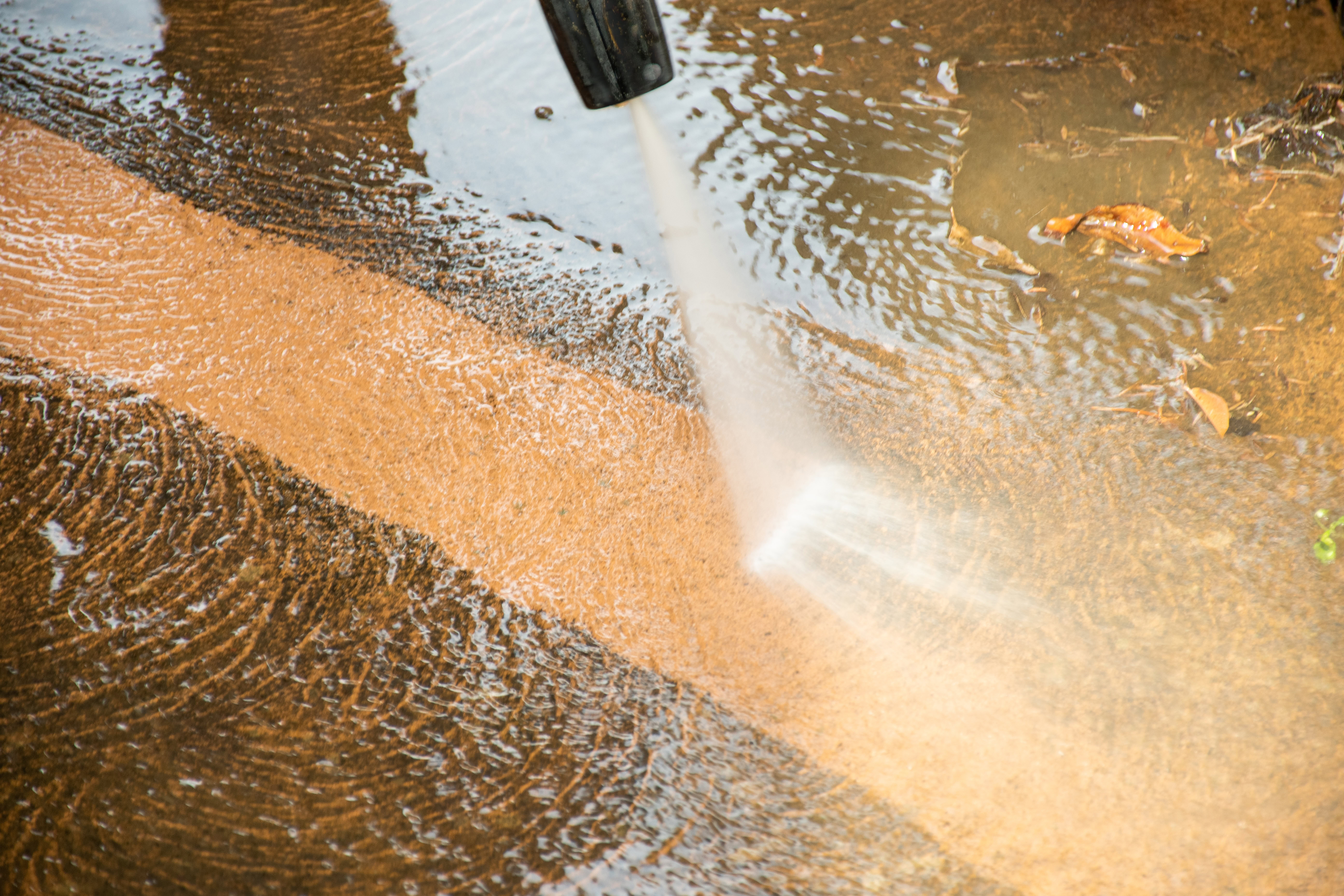pressure washer spraying a concrete surface clean